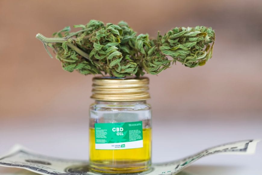 CBD oil in a jar with cannabis bud resting on top
