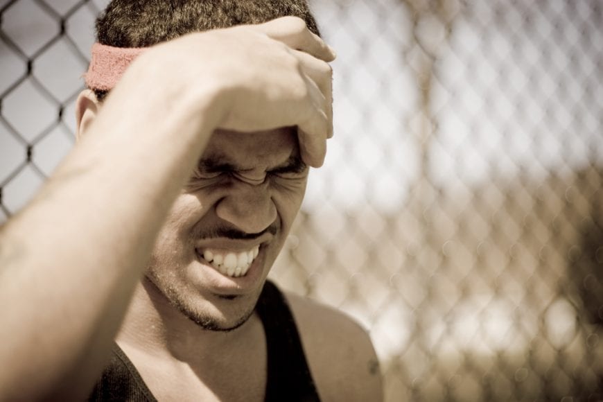 Young Athlete Clutching Head and Grimacing at injured brain