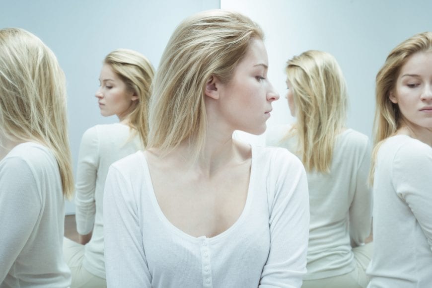 Woman with schizophrenia looking in a carnival mirror that multiplies her image